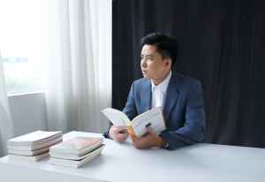 photo of a pensive young man in a suit holding a book