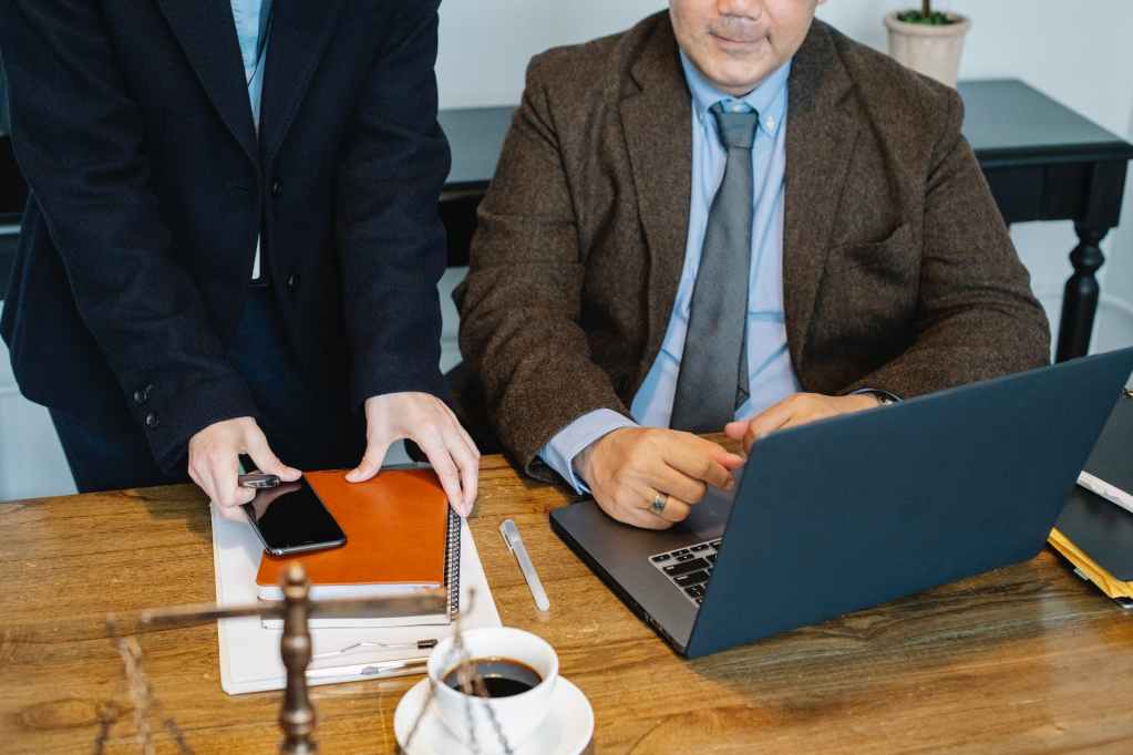 crop colleagues gathering at table with laptop in office
